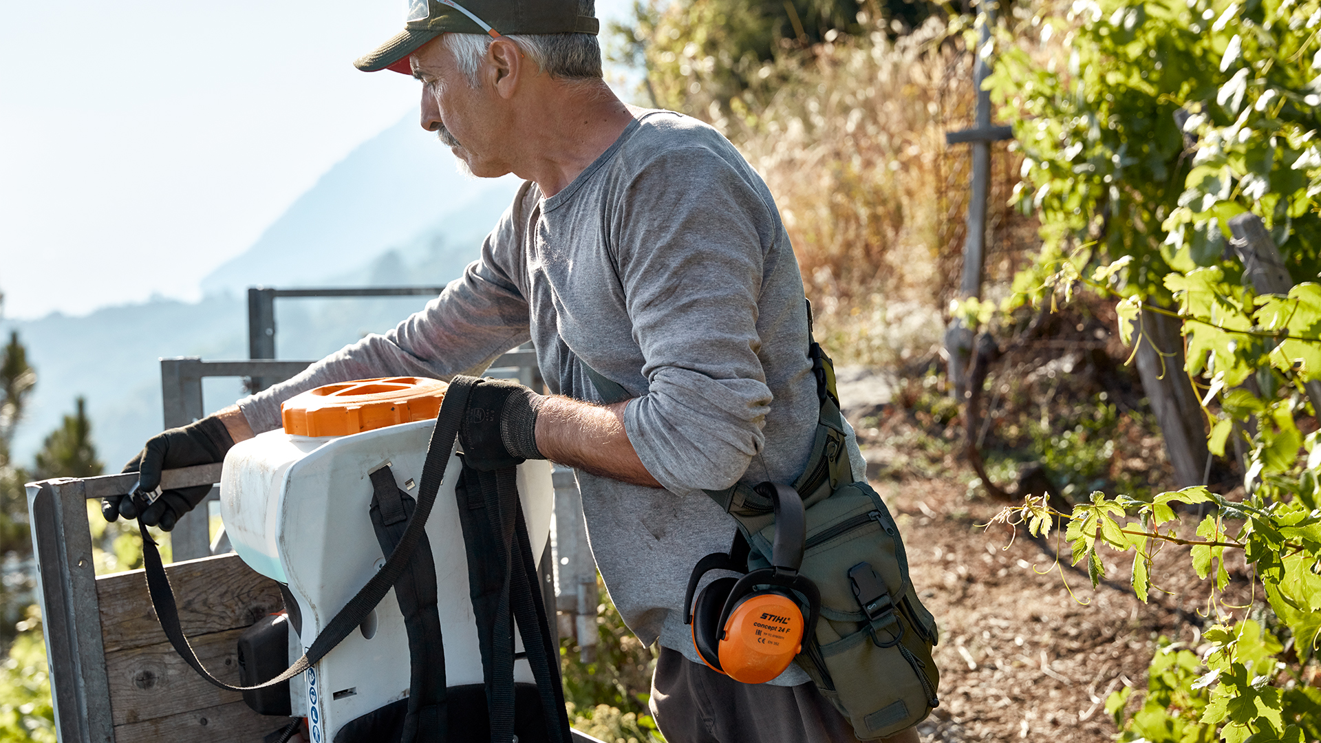 Mann entlädt STIHL Benzin-Sprühgerät SR 200 und Zubehör am Weinberg