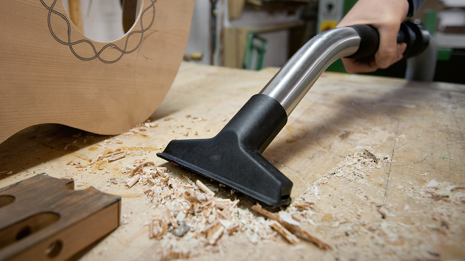 Person saugt Holzreste mit STIHL Trocken/-Nasssauger SE 122 E und Universal-Saugdüse von Werkbank