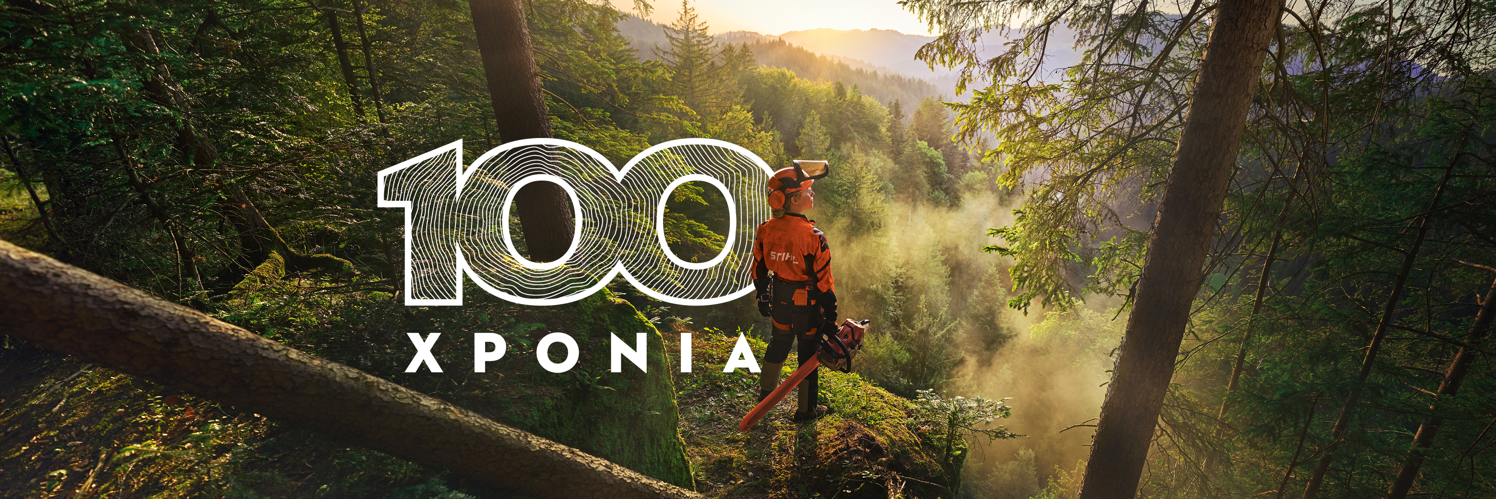 Μία υλοτόμος στο δάσος ατενίζει το και αναγράφεται το λεκτικό 100 χρόνια στα αγγλικά 